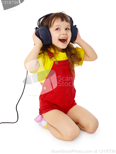 Image of Little girl sitting on white with large earpieces