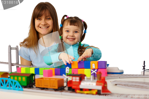 Image of Young mother and daughter playing with toys