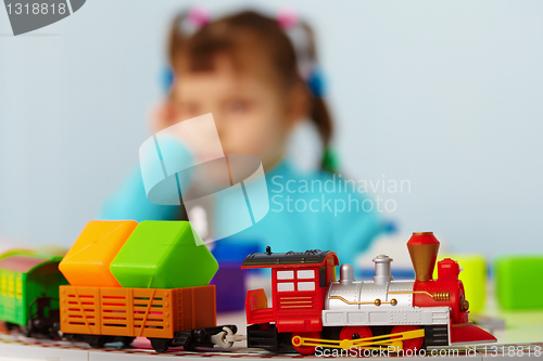 Image of Little girl bored playing with toys alone