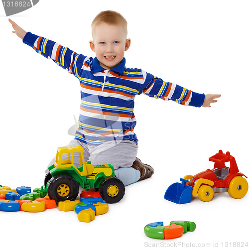 Image of Little boy playing with color toys on floor