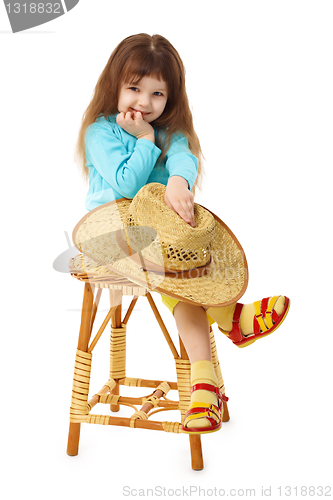 Image of Child sits on an old wooden chair with hat