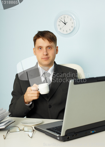 Image of Little tired businessman drinking coffee in office