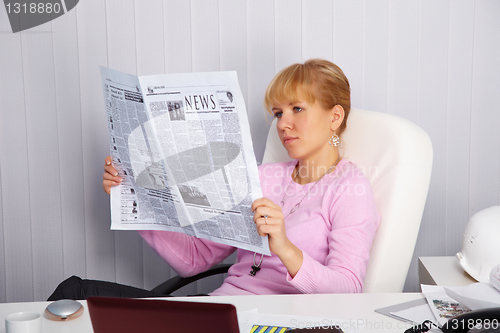 Image of Beautiful young girl reads newspaper