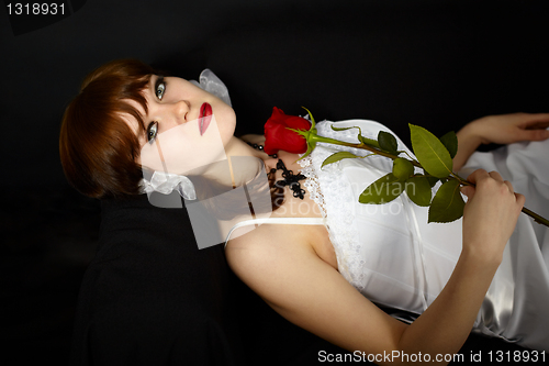 Image of Beautiful girl with rose in hand lying on black
