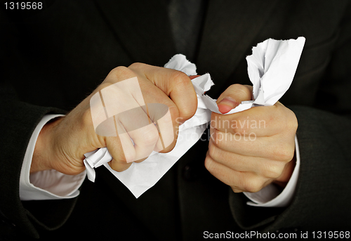 Image of Businessman hands furiously tormenting document