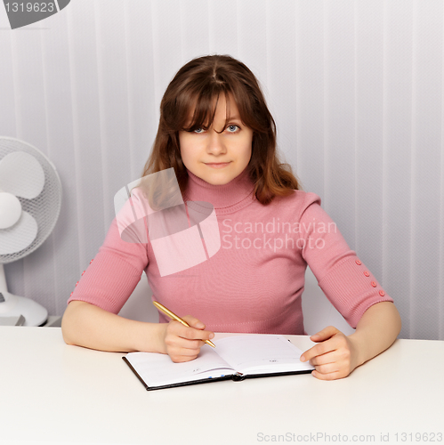 Image of Young woman sits at white table