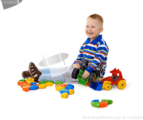 Image of Little boy sitting among toys on floor