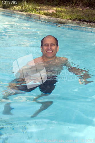 Image of handsome smiling middle age man swimming in pool