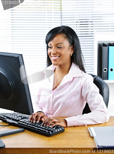 Image of Happy black businesswoman at desk