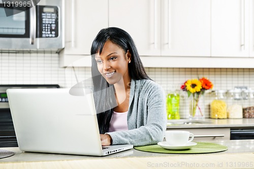 Image of Woman using computer in kitchen