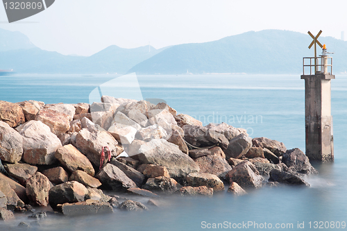 Image of Lighthouse on a Rocky Breakwall: A small lighthouse warns of a r