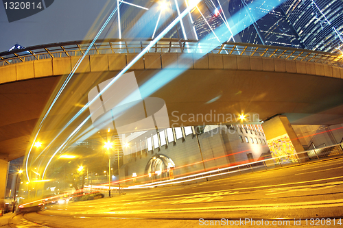 Image of traffic light trails in the street by modern building