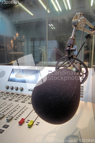 Image of mic in front of the control panel in broadcasting studio 