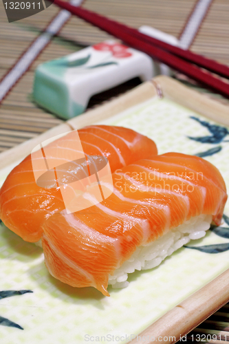 Image of Yummy salmon. A close-up of chopsticks and a square plate with t