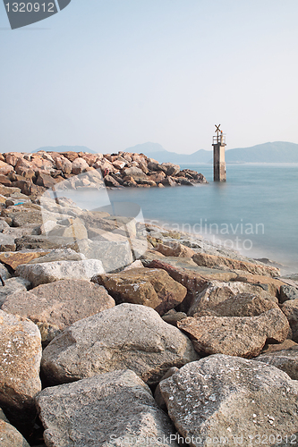 Image of Lighthouse on a Rocky Breakwall: A small lighthouse warns of a r