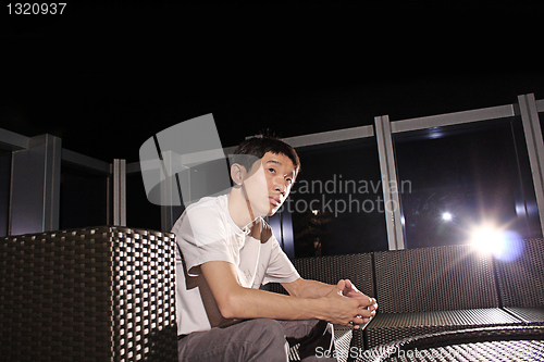 Image of Man sit on a bench while relaxing at a pub. 