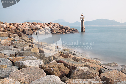 Image of Lighthouse on a Rocky Breakwall: A small lighthouse warns of a r