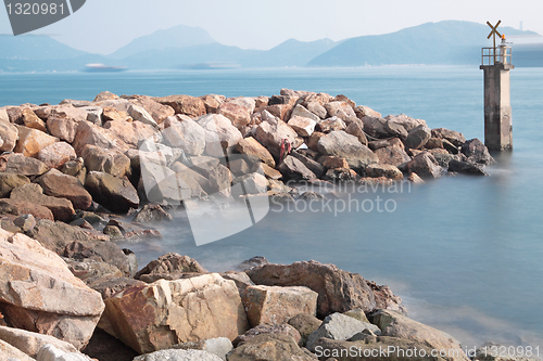 Image of Lighthouse on a Rocky Breakwall: A small lighthouse warns of a r