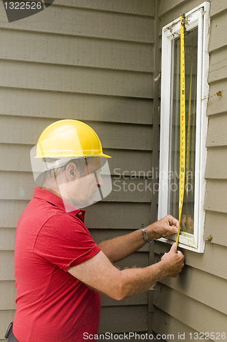 Image of carpenter measuring window repair