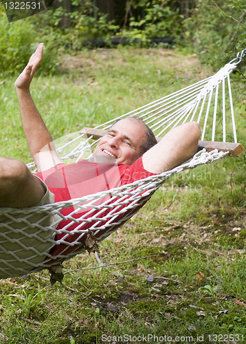 Image of smiling middle age man relaxing in hammock 