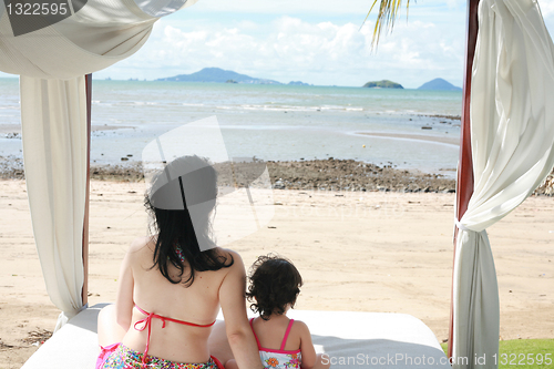 Image of young lovely mother and her little daughter on tropical white be