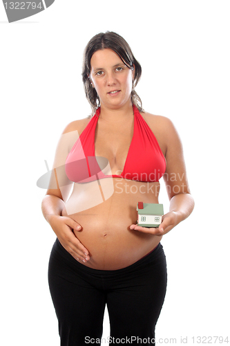 Image of young pregnant woman holding house model over white background 