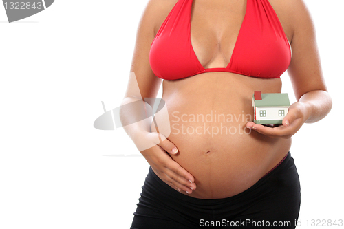 Image of young pregnant woman holding house model over white background 