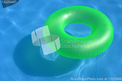 Image of An inflatable green plastic buoy in a shiny blue swimming pool