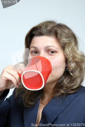 Image of beautiful woman drinking a red mug of coffee