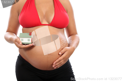 Image of young pregnant woman holding house model over white background 