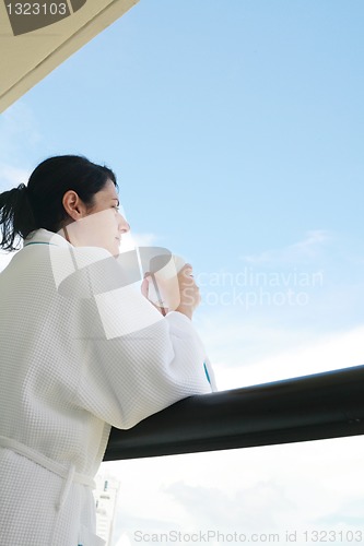 Image of woman with morning coffee looking through balcony
