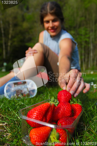 Image of Young woman grabbing for fresh strawberry