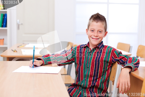 Image of Confident boy sitting alone in classroom