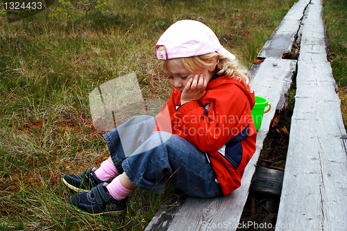 Image of Girl sitting on whethered bench at park