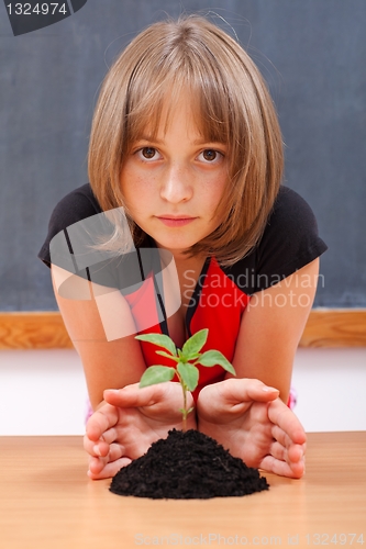 Image of Serious elementary schoolgirl protecting plant