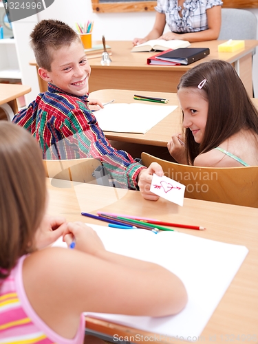 Image of Elementary school boy giving love letter to his colleague