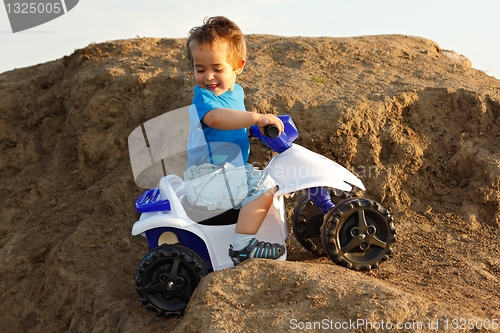 Image of Boy driving toy quad on terrain