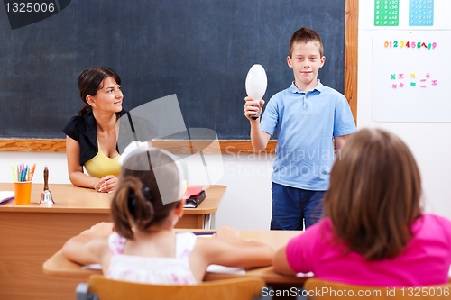 Image of Schoolboy holding bulb in front of class