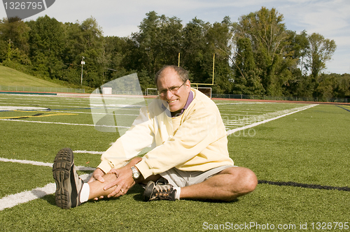 Image of middle age senior man exercising on sports field