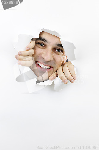 Image of Happy face looking through hole in paper