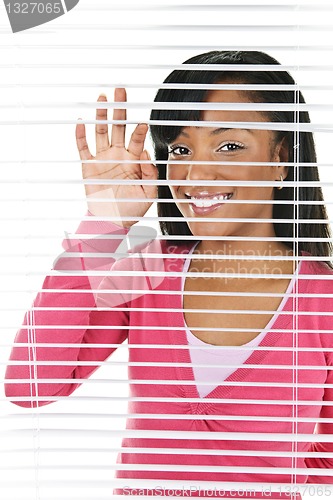 Image of Smiling woman looking through blinds