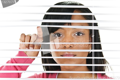 Image of Woman looking through venetian blinds