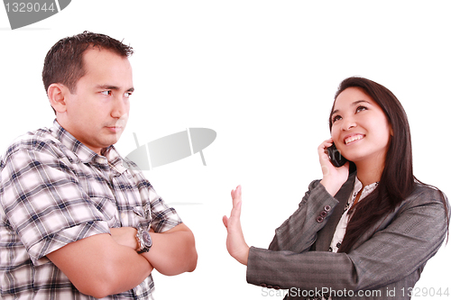Image of smiling businesswoman on the phone signaling his couple to hold 