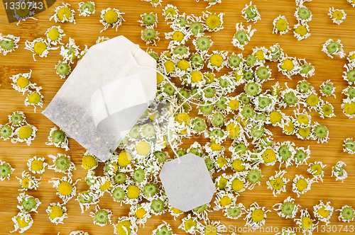 Image of Bag of chamomile tea with dry chamomilla flowers over wooden background