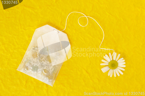 Image of nBag of chamomile tea over yellow handmade paper - concept