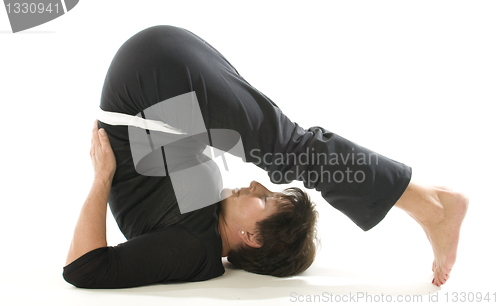 Image of middle age woman demonstrating yoga position halasana the plough