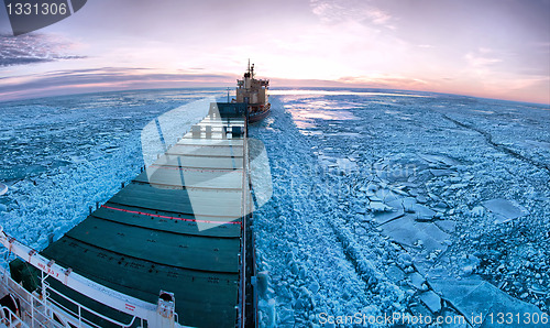 Image of Icebreaker towing cargo ship through thick ice-field