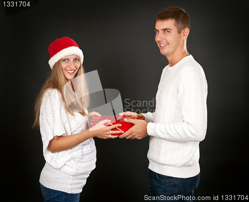 Image of The man gives the gift pregnant girl in Santa hat