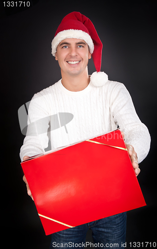 Image of Smiling man in Santa hat gives a red box in the studio