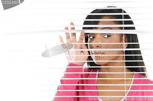 Image of Woman looking through venetian blinds